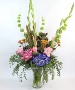 The Monet is designed with fragrant rose lilies, gladiolas and hydrangea, bells of Ireland with fall features of Viking poms, cotinus and cattails.
