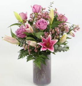 A luxurious bouquet of fragrant Oriental lilies and lavender roses with accents in a clear glass vase.