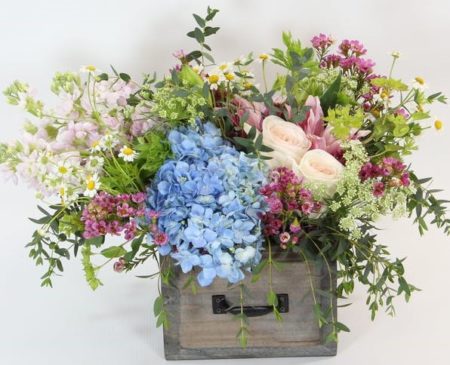 Low and lush, this European-style of hydrangea, fragrant rose lilies, garden roses, fragrant stock and accents of Queen Anne's lace, chamomile and more in a wooden drawer.