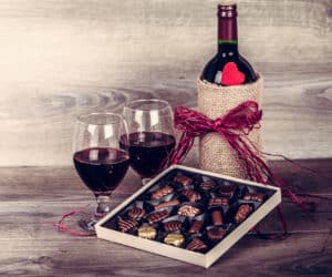 Box of chocolates with bottle of red wine and glasses